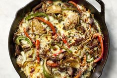 a skillet filled with cheese and vegetables on top of a white countertop next to a spatula