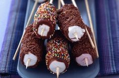 chocolate covered donuts with sprinkles and toothpicks on a plate