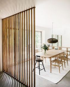 a dining room table and chairs with wooden slats on the wall next to it