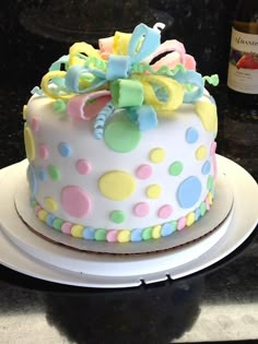 a decorated cake sitting on top of a white plate next to a bottle of wine