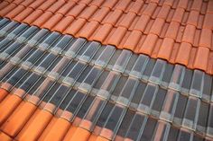 an orange tiled roof is shown in close up with the sky reflected on it's surface