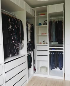 an organized closet with clothes hanging on the shelves and drawers in front of it,