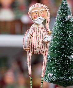 a small christmas tree with a santa clause figure on it's head next to a ceramic ornament