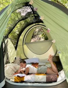 a woman laying in a tent reading a book