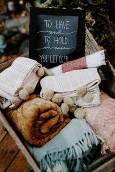 a crate filled with blankets and pillows next to a chalkboard sign that says to have folded you get cold