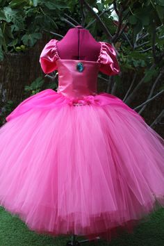 A truly gorgeous shades of Pink ball gown dress inspired by Princess Peach herself. Beautifully handcrafted with hundreds of yards in US  Shades of Pink/ Fuchsia  tulle to make it extra puffy and a satin front bodice with a Blue Jewel Brooch . A beautiful fuchsia organza over-skirt is elegantly draped.  There is also a sewn in pink slip for extra coverage.  The adjustable cap sleeves with ribbon straps tie in the back for the perfect fit! This Tutu dress is amazing for Halloween Parties, Photo s Pink Princess Dress With Fitted Bodice Ball Gown, Pink Princess Dress With Fitted Bodice, Pink Princess Ball Gown With Fitted Bodice, Pink Ball Gown Princess Dress For Debutante Ball, Pink Ball Gown For Debutante Ball, Pink Princess Gown For Fancy Dress, Pink Princess Dress For Debutante Ball, Pink Princess Organza Gown, Pink Princess Style Gown For Fancy Dress