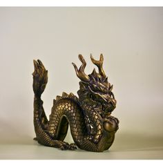 a golden dragon figurine sitting on top of a white table next to a wall