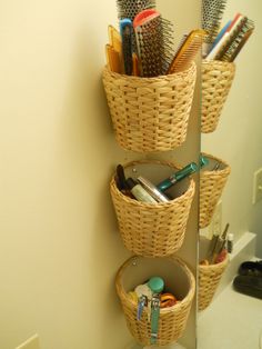 three baskets are stacked on the wall with toothbrushes and other items in them