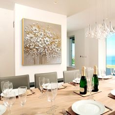 a dining room table is set with wine glasses and champagne bottles in front of an ocean view