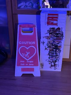 a caution sign sitting on the floor next to a television set with an image of a heart in it