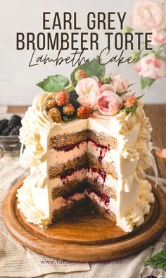 a cake with white frosting and flowers on top is sitting on a wooden platter