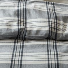 a plaid blanket is folded on top of a bed with two pillow cases next to it