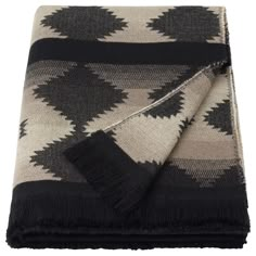 the black and white blanket is folded on top of another blanket, with fringes