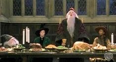 the wizard and his friends sit at a table with food on it in front of them