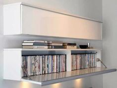 an entertainment center with several different types of cds on the shelves and lights below it