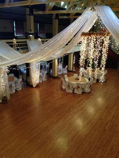 an indoor wedding venue decorated with white draping and lights