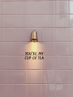 a light that is on the side of a wall next to a cup of tea