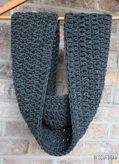 a gray crocheted scarf hanging on a brick wall