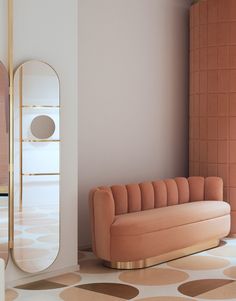 a pink couch sitting next to a tall mirror in a room with polka dots on the floor