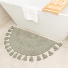 a bath tub sitting next to a white towel on top of a bathroom floor with tassels