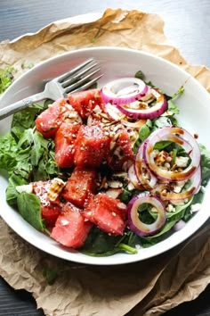 a white bowl filled with watermelon and onions on top of a wooden table