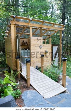 a small wooden structure in the middle of a forest with stairs leading up to it