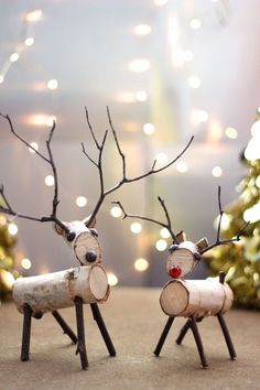 two small wooden reindeers with red noses and antlers made out of wood logs