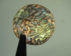 a close up of a metal object with dirt on it's surface and grass growing in the background