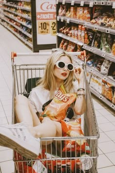 a woman wearing sunglasses sitting in a grocery cart