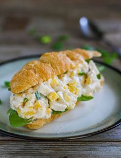 a chicken salad sandwich on a croissant with green leafy garnish