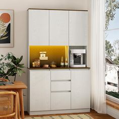 a kitchen with white cabinets and yellow accents on the counter top, along with a potted plant