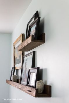 two wooden shelves with pictures and frames on them