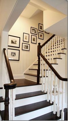 the stairs in this house are white and brown with pictures hanging on the wall above them