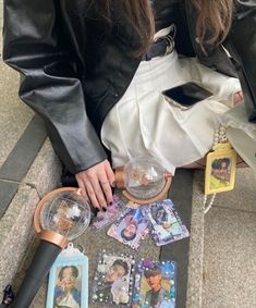 a woman is sitting on the ground with her cell phone and many other items around her