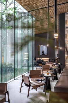 an empty restaurant with chairs and tables in front of glass walls that are reflecting trees