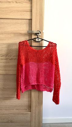 a red sweater hanging on a wooden door