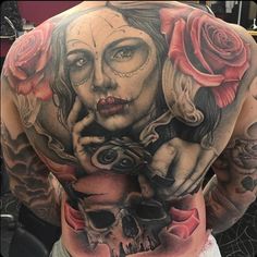 a man with tattoos on his back holding a skull and roses in front of him