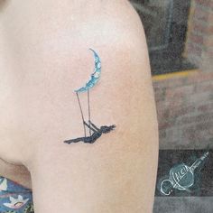 a woman's arm with a tattoo on it that has an image of a bird sitting on the moon