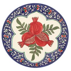 a blue and white plate with pomegranates on the bottom, surrounded by leaves