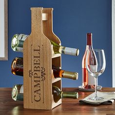 a wooden wine bottle holder with several bottles in it and two glasses on the table