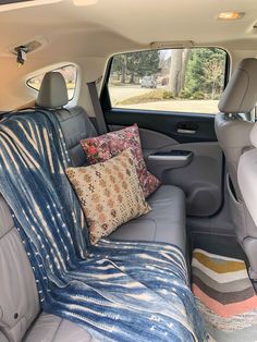 the back seat of a car with a blanket and pillows on it's side