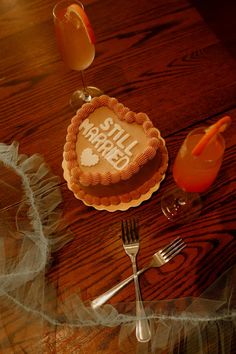 a table topped with a heart shaped cake next to a fork and glass filled with orange juice