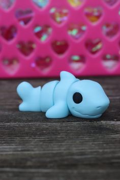 a small blue toy laying on top of a wooden table next to a pink wall