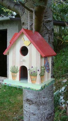 a birdhouse with potted plants on the outside and in the inside, is painted to look like a house