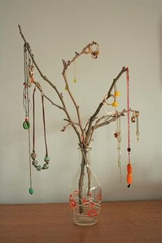 a glass vase filled with jewelry sitting on top of a wooden table next to a tree