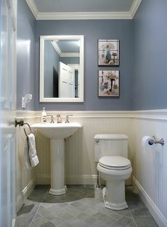 a white toilet sitting next to a sink in a bathroom under a framed mirror on the wall