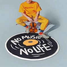 a young man sitting on top of a black and white rug with no music, no life written on it