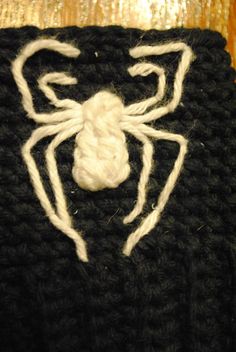 a close up of a knitted spider on top of a wooden table with white thread