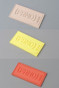 three different colored plastic name tags on a gray surface