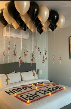 a bed with balloons hanging from it's ceiling and the words happy birthday written on it